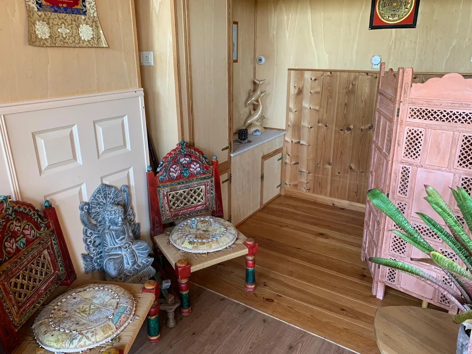 Sfeervol ingerichte hoek met kleurrijke stoelen en een houten kamerscherm